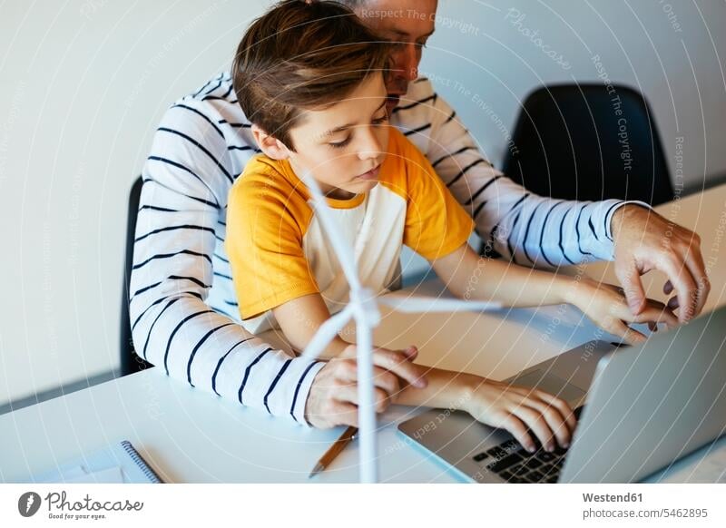 Vater und Sohn mit Laptop neben dem Modell einer Windkraftanlage Windrad Windturbinen Windräder Söhne Notebook Laptops Notebooks Modelle Papas Väter Vati Vatis