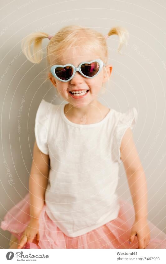 Bildnis eines blonden kleinen Mädchens mit herzförmiger Sonnenbrille Sonnenbrillen Brille Herz Herzform Herzformen Herzen Portrait Porträts Portraits tragen