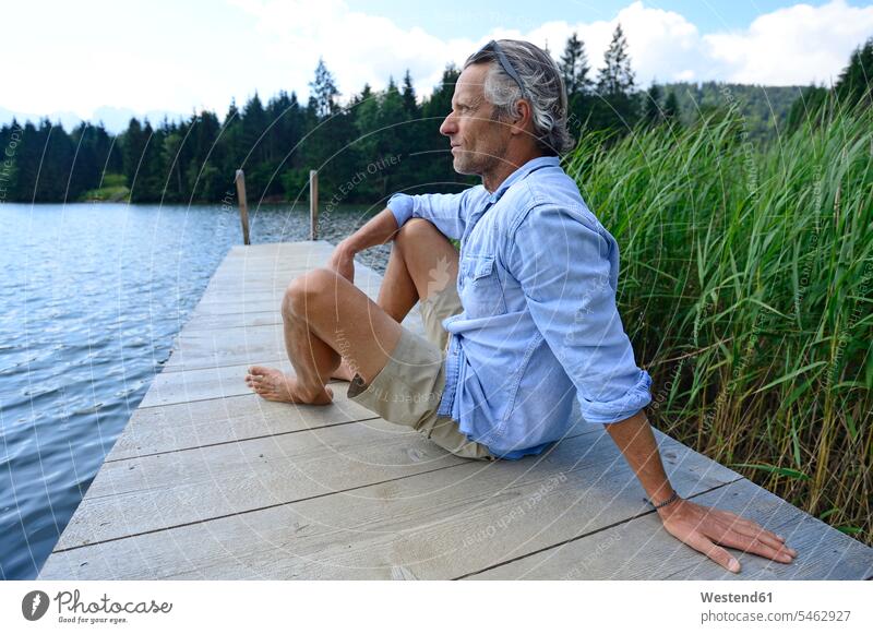Deutschland, Mittenwald, reifer Mann entspannt sich auf dem Bootssteg am See Männer männlich Steg Anleger Stege Landesteg Anlegestellen Landestege Bootsstege