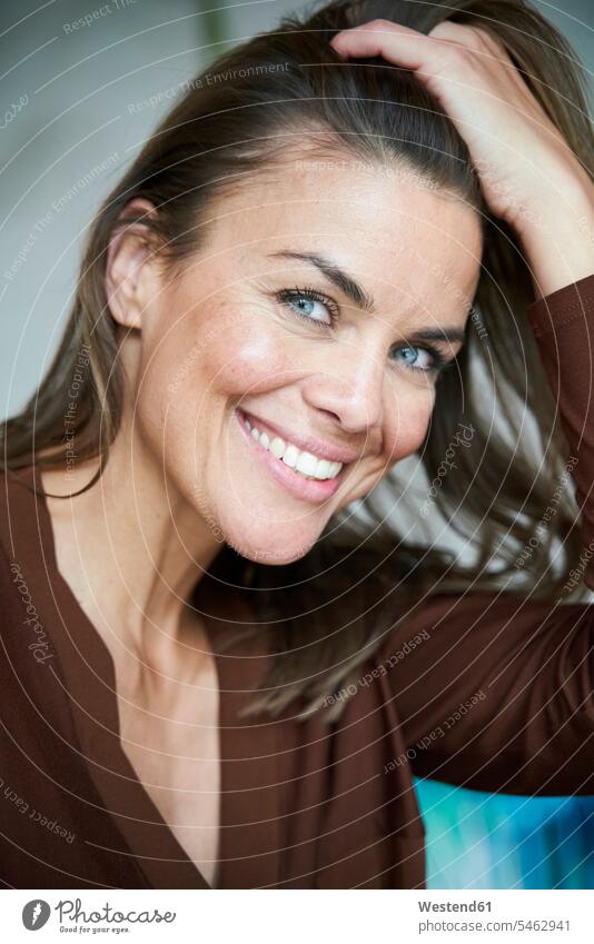 Bildnis einer lächelnden brünetten Frau mit Hand im Haar geschäftlich Geschäftsleben Geschäftswelt Geschäftsperson Geschäftspersonen Businessfrau Businessfrauen