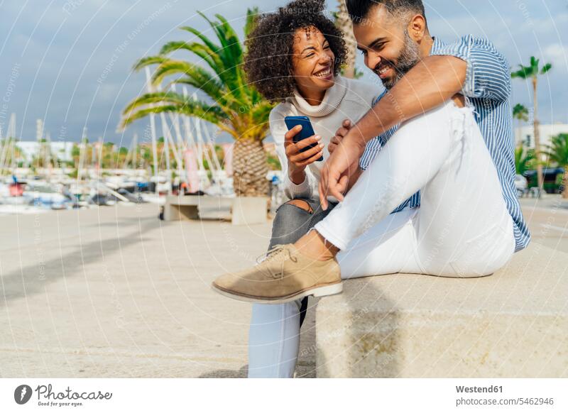 Spanien, Barcelona, glückliches Paar mit Handy am Yachthafen Glück glücklich sein glücklichsein Jachthafen Jachthäfen Yachthaefen Marinas Jachthaefen Yachthäfen