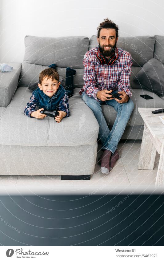 Porträt von Vater und Sohn spielen Computerspiel zusammen auf der Couch Väter Papa Vati Familienvater Papi Computerspiele Sofa Couches Liege Sofas Gemeinsam