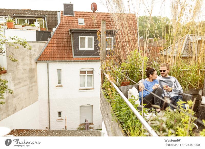 Junges Paar entspannt auf dem Balkon, sitzt auf der Couch Sofa Couches Liege Sofas Balkone liebevoll zaertlich einfühlsam einfuehlsam zärtlich sanft Pärchen
