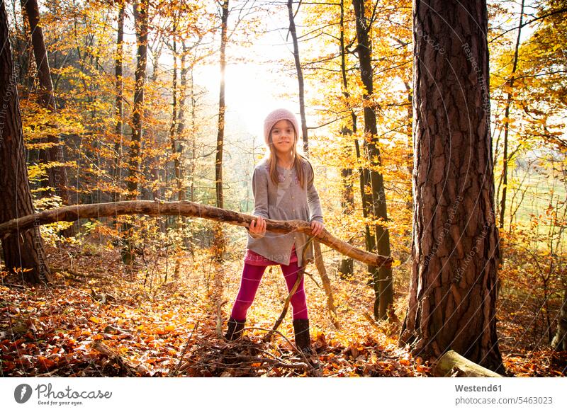 Junges Mädchen hält Zweig im Herbst Wald Kraft stark Stärke kräftig Naturerlebnis stehen stehend steht Ast Aeste Äste weiblich Baum Bäume Baeume Erlebnis