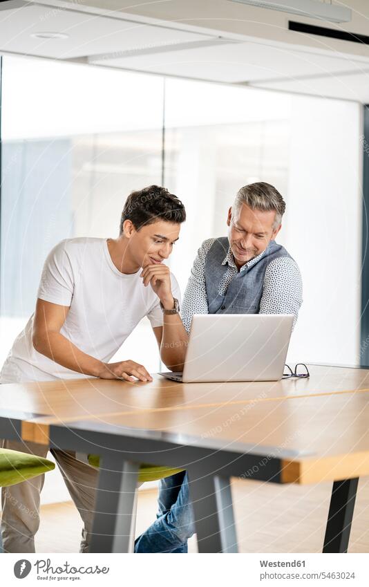 Ein älterer Geschäftsmann arbeitet mit einem jungen Kollegen zusammen und benutzt einen Laptop Europäer zwei Personen junger Mann 20-25 Jahre reifer Mann