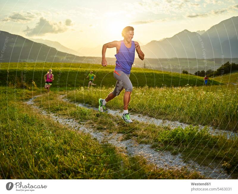 Athleten laufen bei Sonnenuntergang auf dem Feldweg Feldwege Sonnenuntergänge rennen Sportler Weg Wege Pfad Stimmung stimmungsvoll Atmosphäre Ausdauer