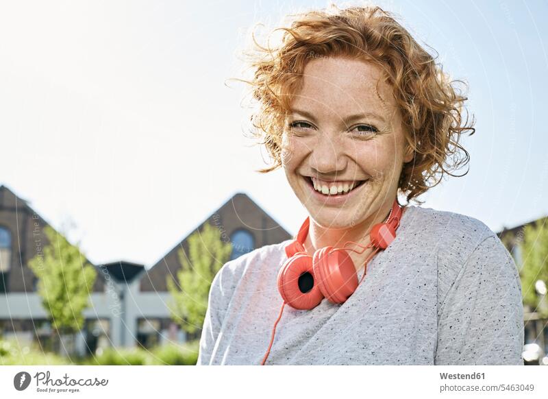 Porträt einer glücklichen jungen Frau mit Kopfhörern in städtischer Umgebung weiblich Frauen Kopfhoerer Urban Urbanität Urbanitaet Glück glücklich sein