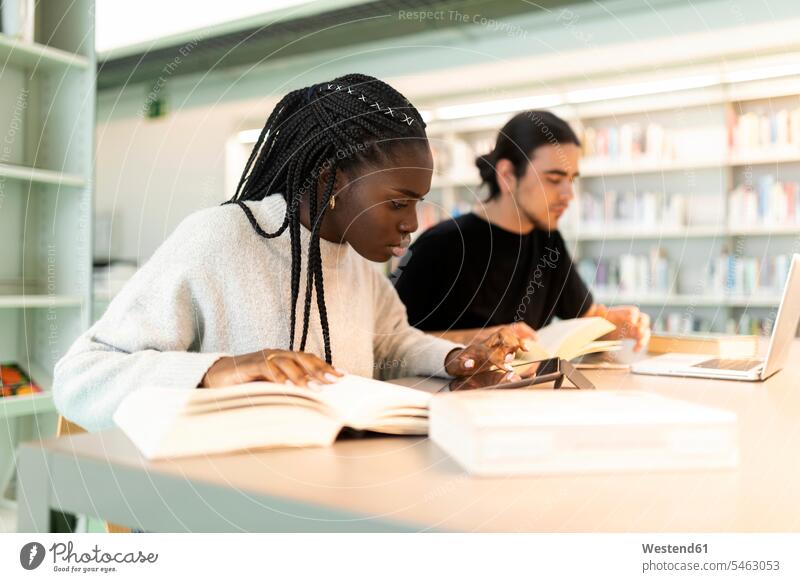 Zwei Studenten lernen in einer Bibliothek Freunde Buch Tisch lesen sitzen studieren Gemeinsam Internet Konzentration Lifestyle Mobilität Online Verbindung