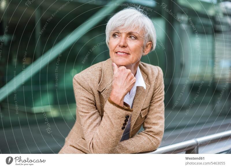 Porträt einer älteren Geschäftsfrau, die sich auf ein Geländer in der Stadt stützt und sich umschaut Geschäftsfrauen Businesswomen Businessfrauen Businesswoman
