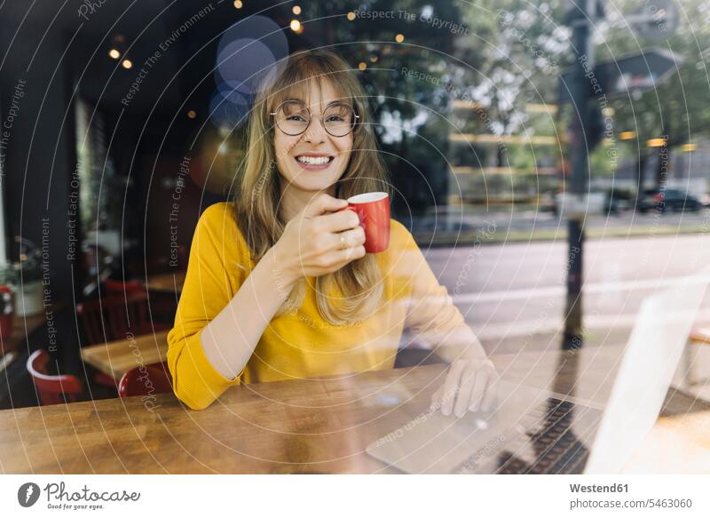 Porträt einer lächelnden Frau mit Laptop und Kaffee in einem Cafe Job Berufe Berufstätigkeit Beschäftigung Jobs geschäftlich Geschäftsleben Geschäftswelt