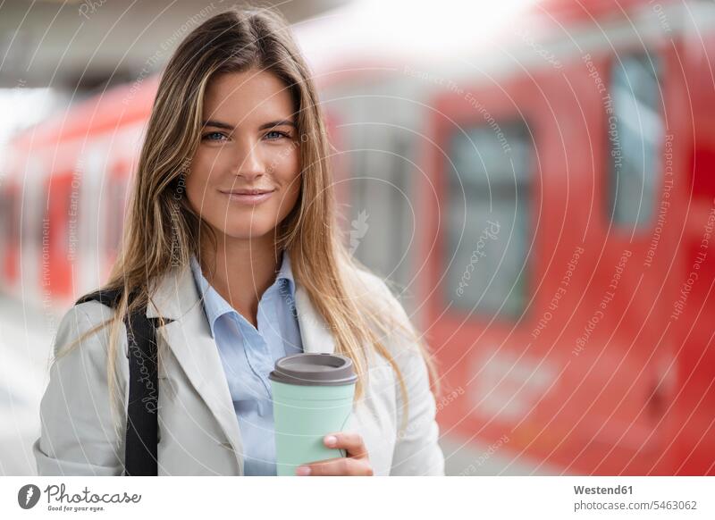 Junge Geschäftsfrau mit Kaffee zum Mitnehmen, auf dem Bahnhof stehend Leute Menschen People Person Personen Europäisch Kaukasier kaukasisch 1 Ein ein Mensch