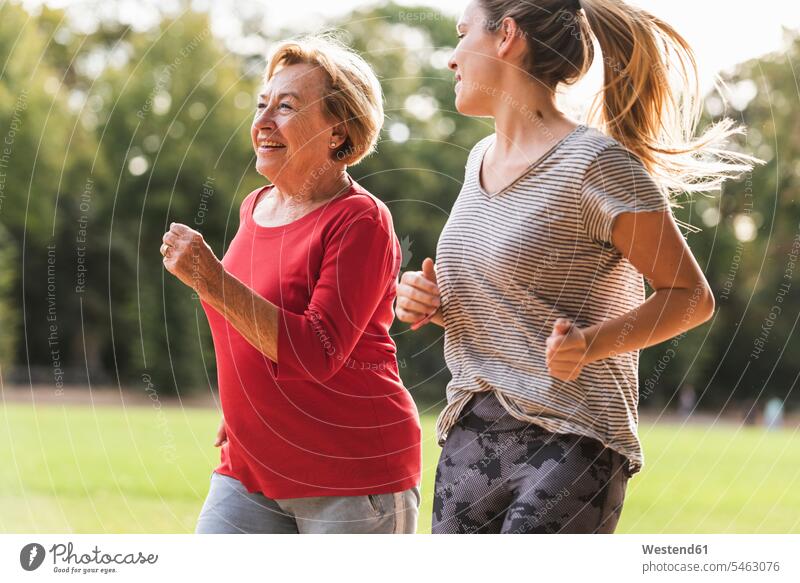 Enkelin und Großmutter haben Spaß, joggen zusammen im Park Grossmutter Oma Grossmama Großmütter Omi Enkeltochter Enkelinnen Enkeltöchter Gemeinsam Zusammen