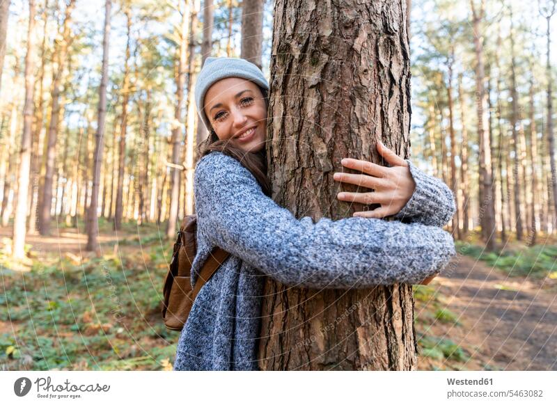 Lächelnde Wanderin umarmt Baumstamm bei der Erkundung im Wald von Cannock Chase Farbaufnahme Farbe Farbfoto Farbphoto Außenaufnahme außen draußen im Freien Tag