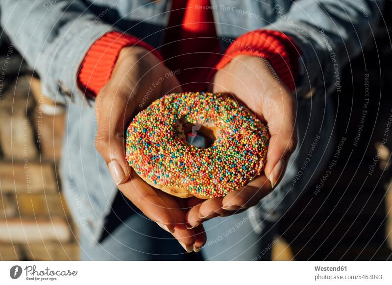 Nahaufnahme der Hände einer jungen Frau, die einen Donut hält Farbaufnahme Farbe Farbfoto Farbphoto Irland Republik Irland Freizeitkleidung Freizeitbekleidung