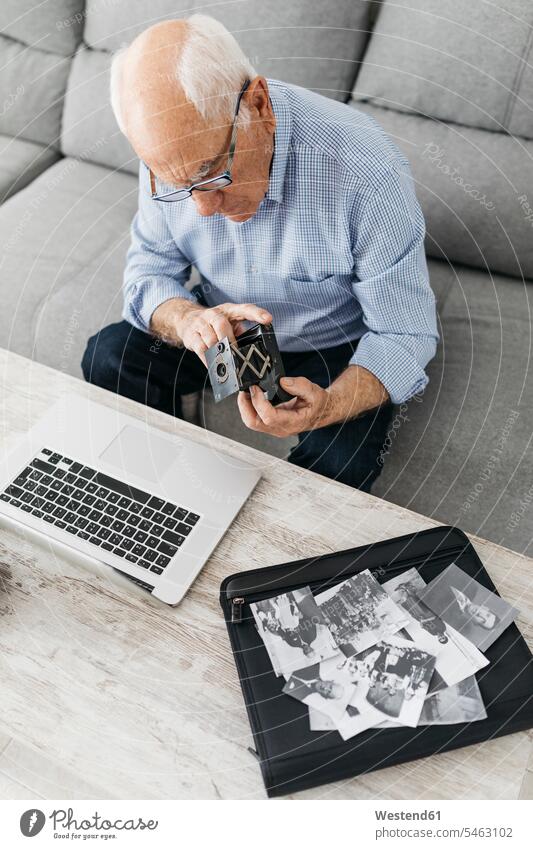 Älterer Mann benutzt Laptop und hält seine alte Fotokamera, alte Fotos auf Laptop-Tasche Drahtlose Technologie drahtlose Verbindung Drahtlose Kommunikation