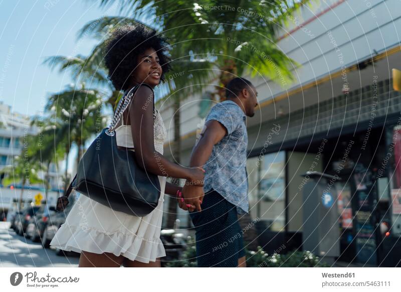 USA, Florida, Miami Beach, glückliches junges Paar beim Überqueren der Straße Pärchen Paare Partnerschaft Strassen Straßen gehen gehend geht Glück