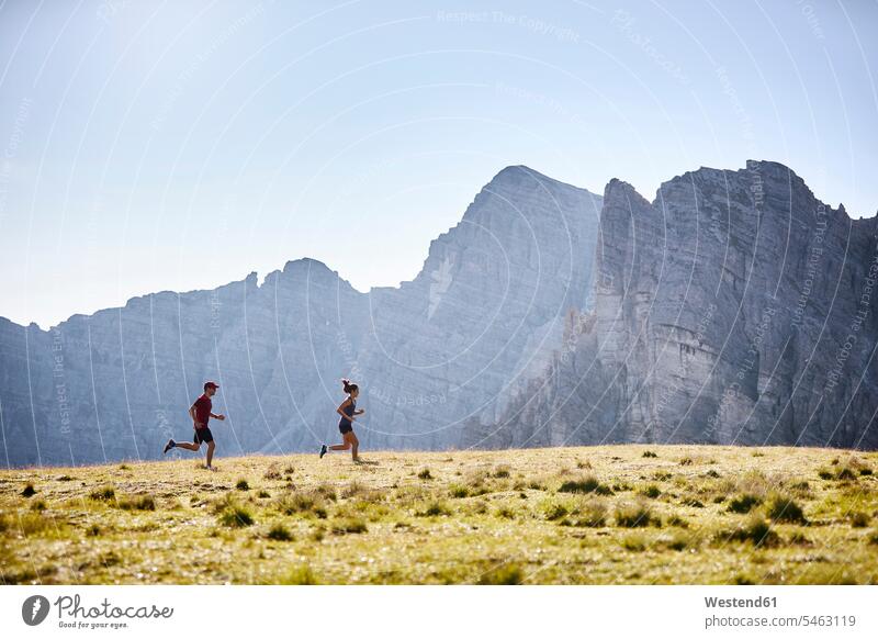 Mann und Frau laufen in den Bergen Jahreszeiten sommerlich Sommerzeit Leistungen frei Miteinander Zusammen Schnelligkeit Anreiz Ansporn Antrieb motivieren