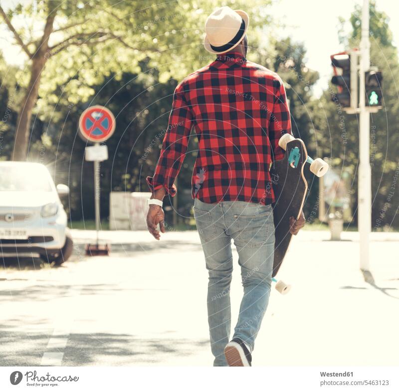 Cooler junger Mann mit Skateboard in der Stadt unterwegs, Rollbretter Skateboards auf Achse in Bewegung Männer männlich cool Coolness gehen gehend geht Straße