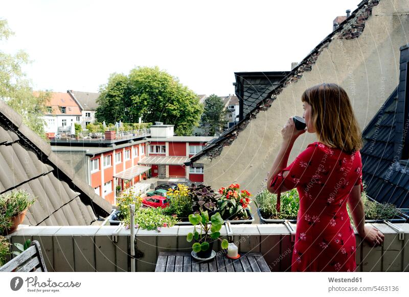 Junge Frau entspannt mit einer Tasse Kaffee auf dem Balkon und schaut in die Ferne Leute Menschen People Person Personen Europäisch Kaukasier kaukasisch 1 Ein