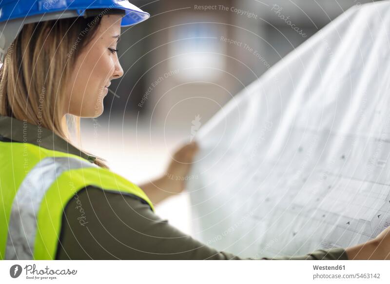 Frau mit Schutzhelm schaut auf Bauplan weiblich Frauen Architekturplan Bauzeichnung ansehen Bauhelm Schutzhelme Bauhelme Helm Erwachsener erwachsen Mensch