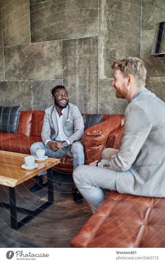 Zwei glückliche Geschäftsleute bei einer Kaffeepause in der Hotellobby geschäftlich Geschäftsleben Geschäftswelt Geschäftsperson Geschäftspersonen