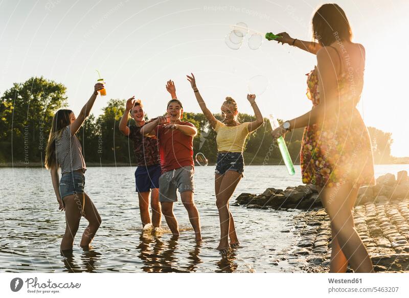 Gruppe glücklicher Freunde in einem Fluss bei Sonnenuntergang Gruppe von Menschen Menschengruppe Fluesse Fluß Flüsse Sonnenuntergänge Glück glücklich sein