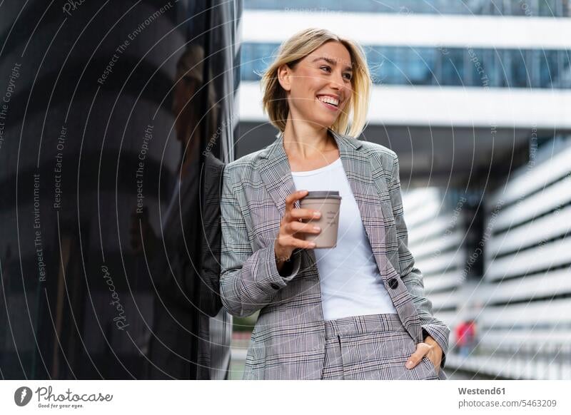 Fröhliche junge Geschäftsfrau mit Kaffee zum Mitnehmen in der Stadt geschäftlich Geschäftsleben Geschäftswelt Geschäftsperson Geschäftspersonen Businessfrau