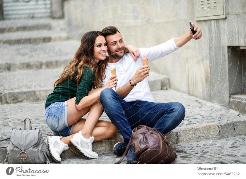 Touristenpaar mit Eistüten in der Stadt, das ein Selfie macht Paar Pärchen Paare Partnerschaft Eistuete Eiswaffel Selfies Speiseeis Zuneigung staedtisch