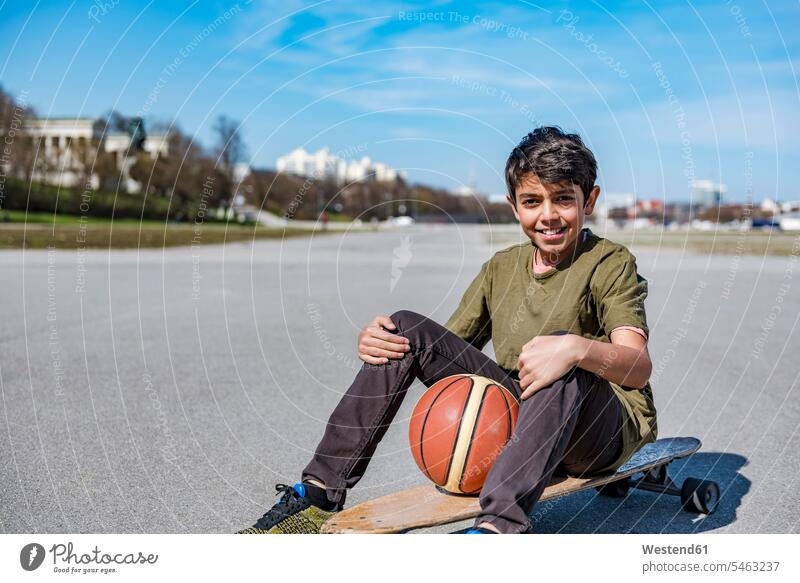 Porträt eines lächelnden Jungen mit Longboard und Basketball im Freien Basketbaelle Basketbälle Buben Knabe Knaben männlich Portrait Porträts Portraits Sport