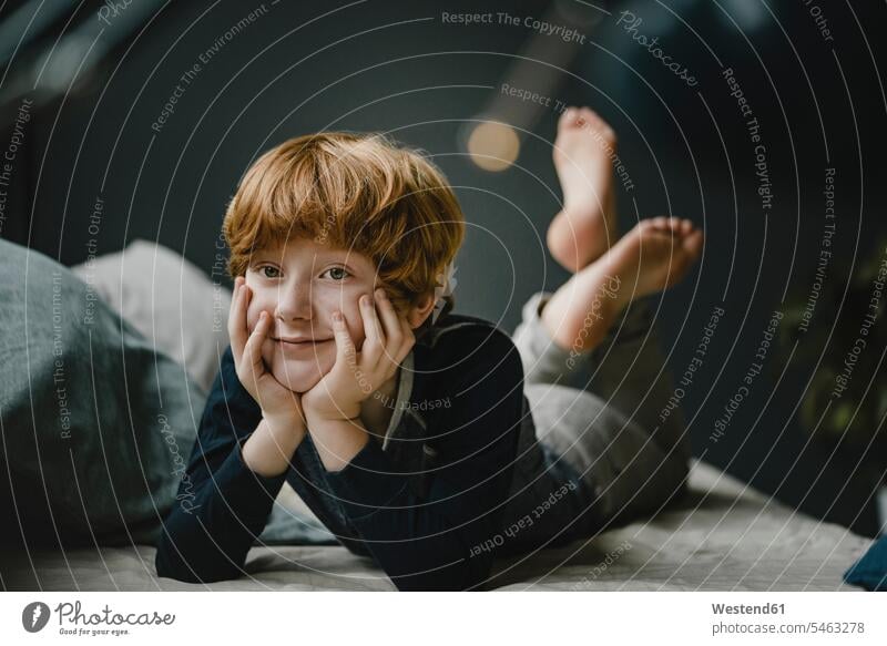 Porträt eines lächelnden rothaarigen Jungen, der zu Hause auf der Couch liegt Leute Menschen People Person Personen Europäisch Kaukasier kaukasisch 1 Ein