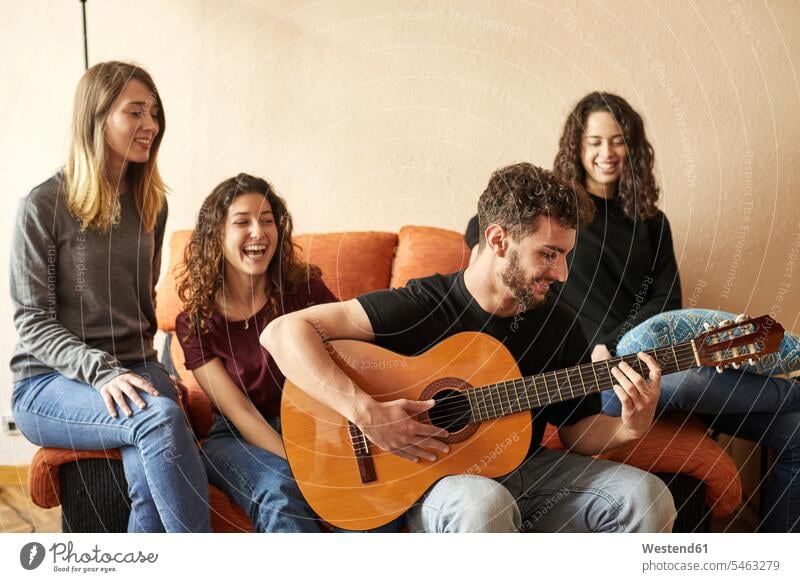 Glückliche Freunde hören einem Mann beim Gitarrespielen auf dem Sofa zu Gruppe Gruppe von Menschen Menschengruppe glücklich glücklich sein glücklichsein