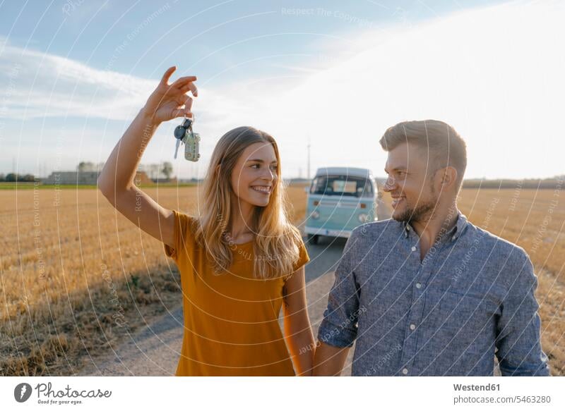 Junges Paar mit Autoschlüssel auf Feldweg an Wohnmobil in ländlicher Landschaft Schlüssel glücklich Glück glücklich sein glücklichsein auf dem Land