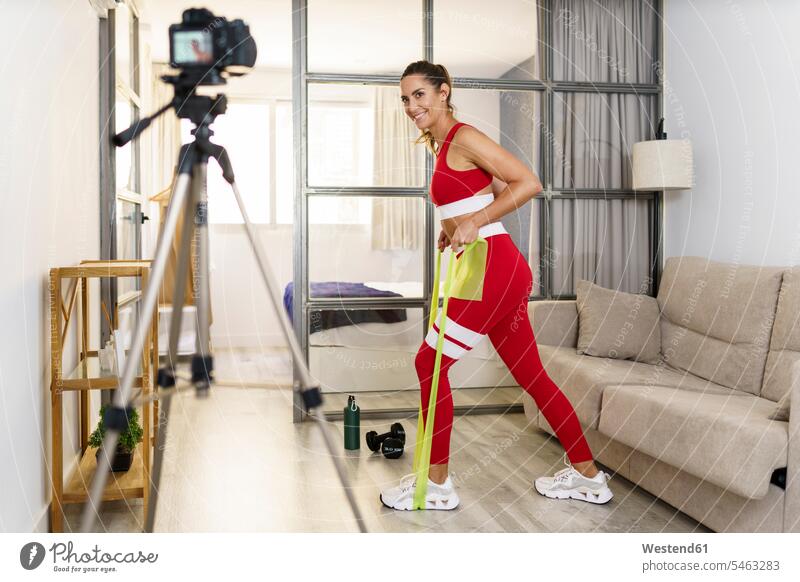 Fitnesstrainer nimmt die Übung mit der Kamera zu Hause auf Farbaufnahme Farbe Farbfoto Farbphoto Innenaufnahme Innenaufnahmen innen drinnen Tag