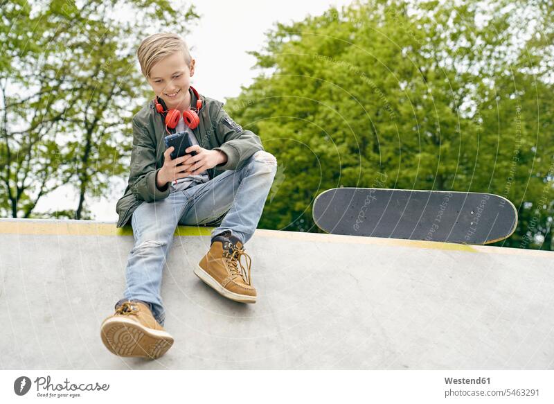 Junge mit Kopfhörern im Skatepark mit Smartphone Kopfhoerer iPhone Smartphones Skateboarder Skateboardfahrer Skateboarders Skater Buben Knabe Jungen Knaben