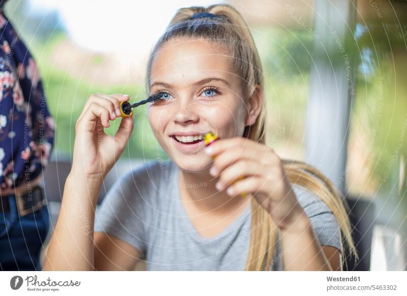 Porträt einer lächelnden Teenagerin beim Auftragen von Wimperntusche Mascara junges Mädchen Teenagerinnen weiblich junge Frau schminken Portrait Porträts