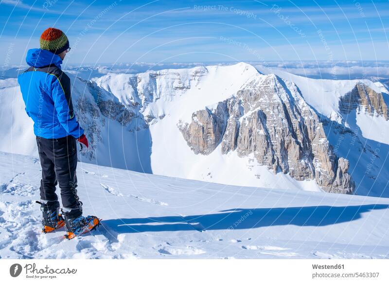 Junger Mann betrachtet Aussicht, während er auf einem schneebedeckten Berg steht, Umbrien, Italien Farbaufnahme Farbe Farbfoto Farbphoto Sibillinische Berge