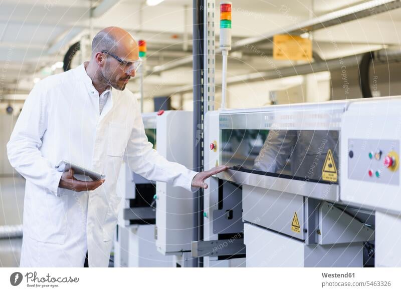 Ein reifer männlicher Techniker hält ein digitales Tablett und untersucht Maschinen in der Fabrik Farbaufnahme Farbe Farbfoto Farbphoto Innenaufnahme