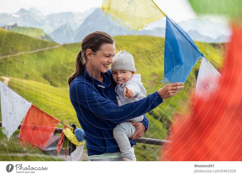 Deutschland, Bayern, Oberstdorf, glückliche Mutter mit kleiner Tochter auf einer Berghütte umgeben von Wimpeln Mamas Mami Mutti Mütter Muetter Mamis Muttis