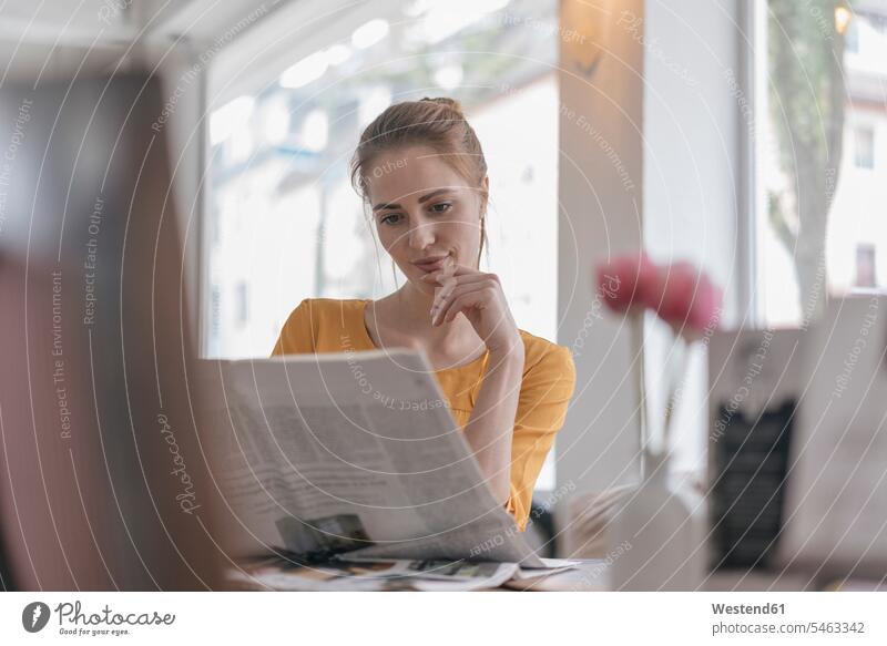 Junge Frau sitzt im Coworking Space und liest Zeitung Cafe Kaffeehaus Bistro Cafes Café Cafés Kaffeehäuser Zeitungen lesen Lektüre sitzen sitzend weiblich