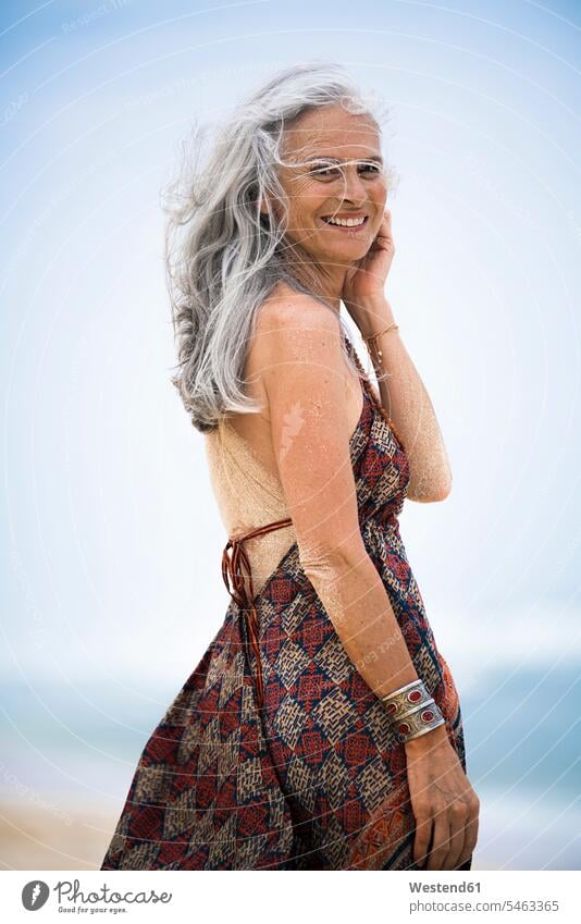 Porträt der lächelnden älteren Hippie-Frau mit sandigen Rücken am Strand weiblich Frauen Portrait Porträts Portraits Sand Beach Straende Strände Beaches Hippies