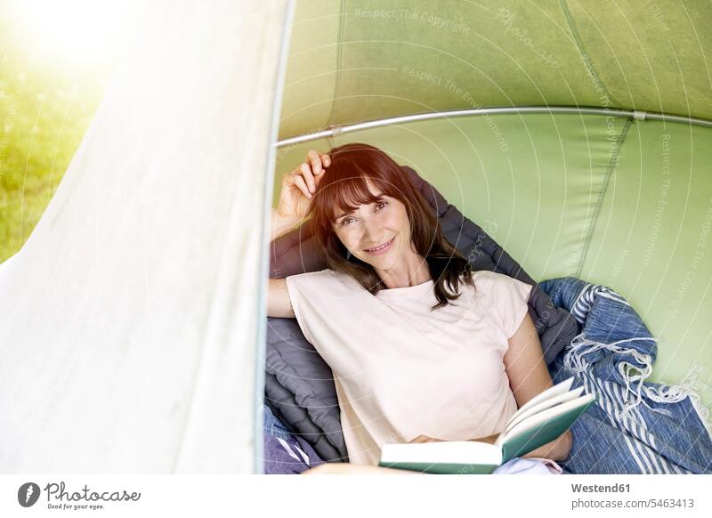Porträt einer lächelnden Frau, die in einem hängenden Zelt ein Buch liest Leute Menschen People Person Personen Europäisch Kaukasier kaukasisch 1 Ein ein Mensch