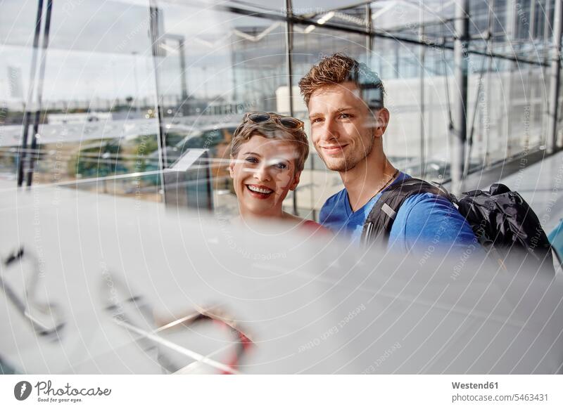 Porträt eines lächelnden Paares am Flughafen mit Blick aus dem Fenster Portrait Porträts Portraits schauen sehend Pärchen Partnerschaft Flughaefen Flugplätze