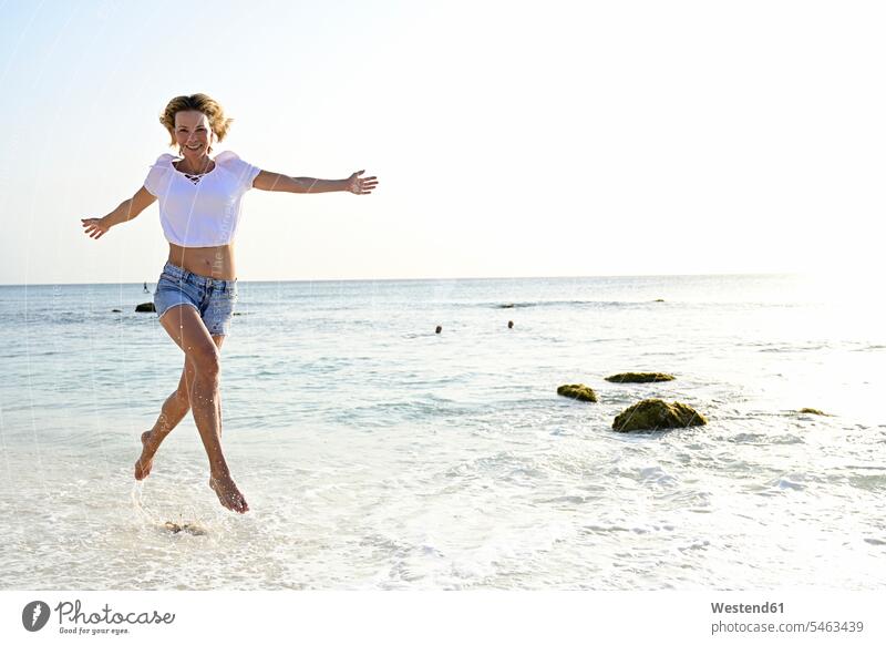 Schöne Frau rennt und springt vor Freude am Strand rennen freuen Frohsinn Fröhlichkeit Heiterkeit Glück glücklich sein glücklichsein Dynamik dynamisch Power