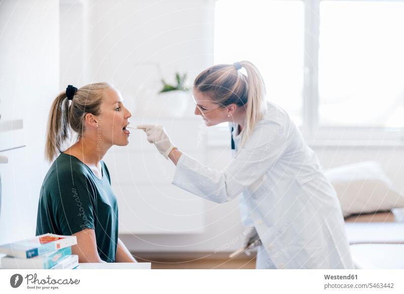 Ärztin untersucht Patientin mit Zungenspatel Job Berufe Berufstätigkeit Beschäftigung Jobs Brillen Arbeit Gesundheit Gesundheitswesen medizinisch Arztpraxen