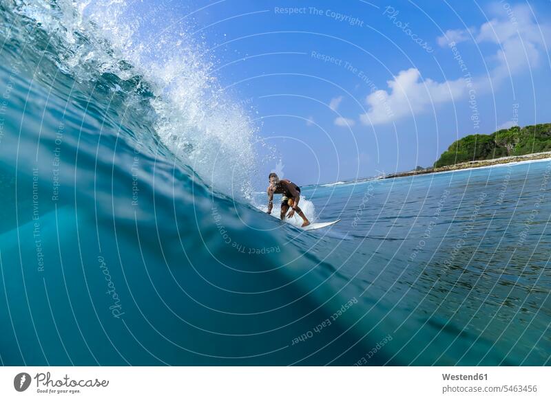 Mann surft auf der Welle mit Surfbrett im Meer gegen den Himmel Farbaufnahme Farbe Farbfoto Farbphoto Außenaufnahme außen draußen im Freien Tag