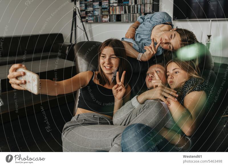 Freunde gestikulieren, während sie sich zu Hause auf dem Sofa vergnügen Farbaufnahme Farbe Farbfoto Farbphoto Deutschland Innenaufnahme Innenaufnahmen innen