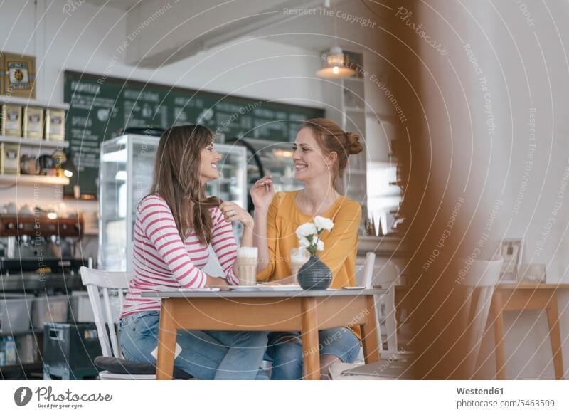 Zwei Freundinnen treffen sich in einem Café und unterhalten sich Treffen Begegnung sprechen reden sitzen sitzend sitzt Cafe Kaffeehaus Bistro Cafes Kaffeehäuser