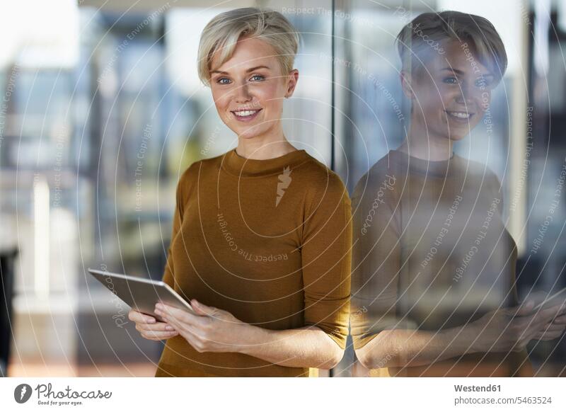 Porträt einer lächelnden Geschäftsfrau mit Tablette am Fenster Geschäftsfrauen Businesswomen Businessfrauen Businesswoman anlehnen angelehnt lehnend Portrait