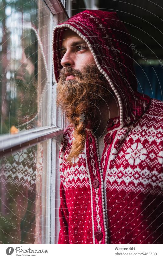 Porträt eines nachdenklichen Mannes mit Bart und Kapuzenjacke, der aus dem Fenster schaut schauen sehend Bärte Portrait Porträts Portraits Kapuzenjacken Mensch