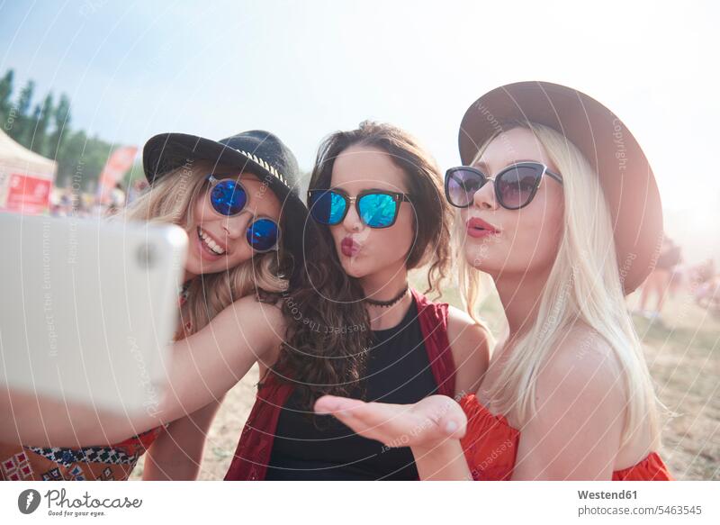Glückliche Freunde, die beim Musikfestival ein Video drehen, kräuselnde Lippen Selfie Selfies Smartphone iPhone Smartphones Videofilm Videos fotografieren